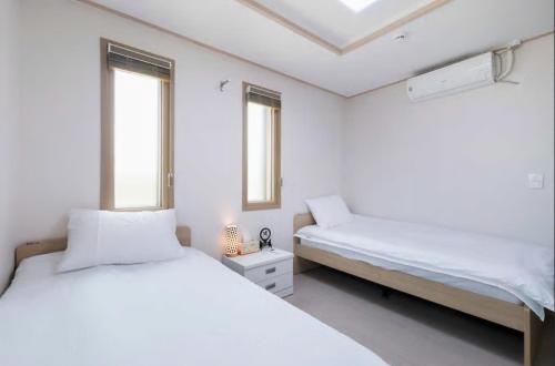 仁川市哈布旅馆的白色客房的两张床,设有两扇窗户
