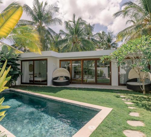 龙目岛库塔Kalea Villas的棕榈树屋前的游泳池