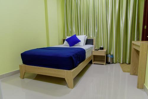 马累Tourist Inn的一间卧室配有一张带蓝色棉被的床