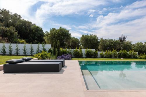 卡兰兹拉Five Senses Of Luxury的后院的游泳池旁设有沙发