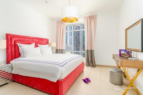 迪拜Dream Inn Apartments - Burj Views的一间卧室配有红色的床、一张书桌和一个窗户。
