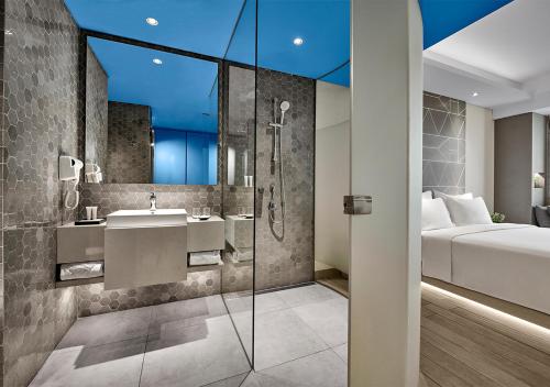 芝卡朗Nuanza Hotel & Convention Cikarang的带淋浴和盥洗盆的浴室以及1张床。