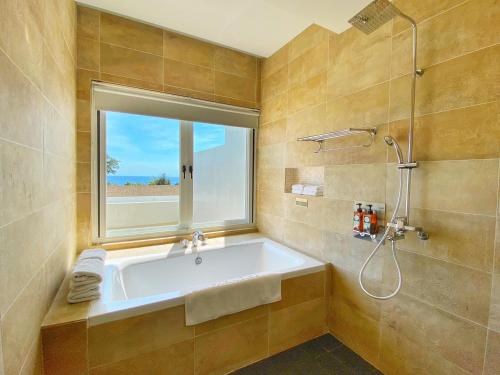 恒春古城垦丁海境渡假民宿 的带浴缸的浴室和窗户。