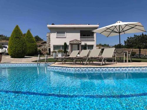 普拉奇里奥Villa Casa Chrissy的一个带椅子和遮阳伞的游泳池以及一间房屋
