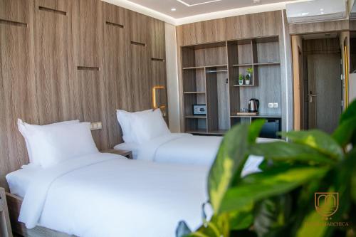 纳祖尔Marchica Hotel的配有白色枕头的酒店客房内的两张床