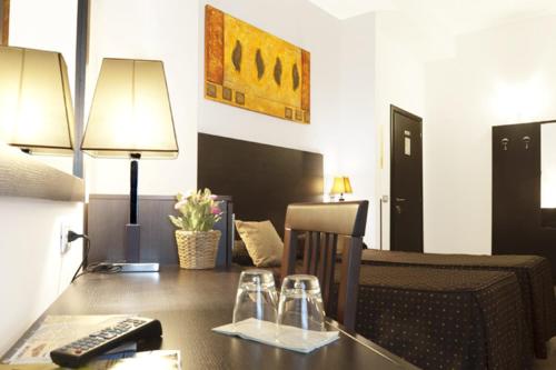 罗马罗马度假村酒店的客房设有一张桌子、一张沙发和一张带遥控器的桌子。