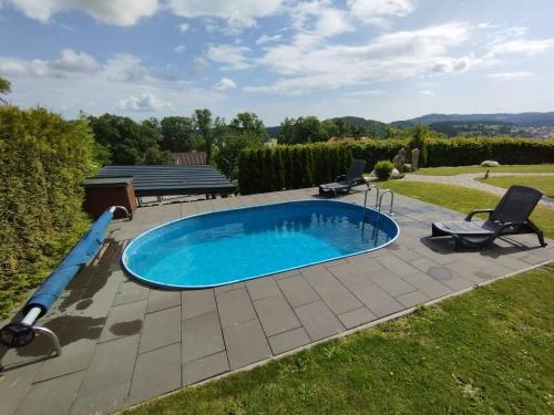 温佩尔克Vila Albrecht Vimperk的庭院内的游泳池,配有两把草坪椅和游泳池