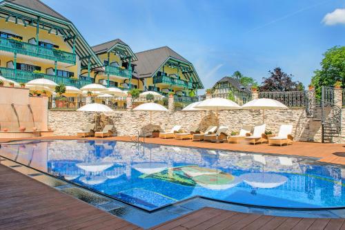 阿尼夫弗里萨切酒店的度假村的游泳池,配有椅子和遮阳伞