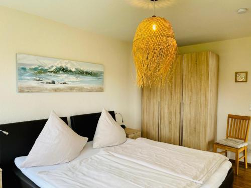 希尔克道夫FeWo PANORAMADECK Familien-strandnah-Garten-Hunde-Sport-und Schwimmbadnah-HansaPark的一间卧室配有一张带白色床单和吊灯的床。