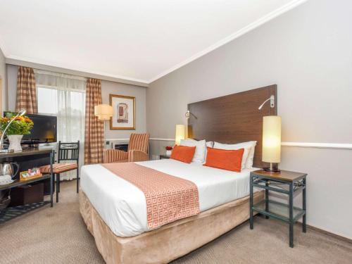 米德兰约翰内斯堡米德兰美居酒店的酒店客房设有一张大床和一张书桌。