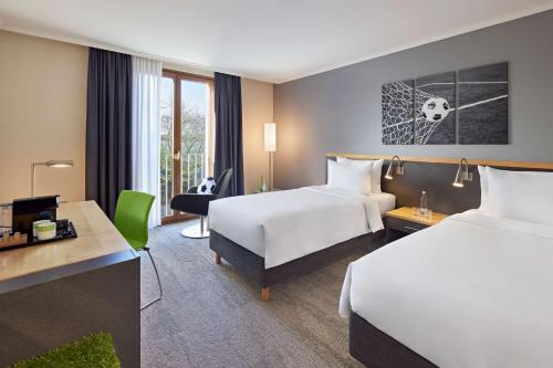 勒沃库森Lindner Hotel Leverkusen BayArena, part of JdV by Hyatt的酒店客房配有两张床和一张书桌