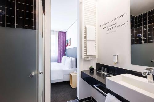 美因河畔法兰克福Lindner Hotel Frankfurt Sportpark, part of JdV by Hyatt的一间带水槽的浴室和一张位于客房内的床