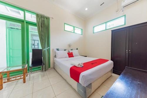 苏加武眉RedDoorz @ Jalan R.E. Martadinata Sukabumi的一间卧室配有一张床、一把椅子和窗户。