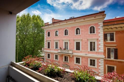 罗马77号家庭食宿酒店的一座粉红色的建筑,阳台上种有树木和鲜花
