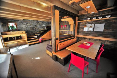 奥瓦罗Chalet Al Cucù的一间带桌子和红色椅子的用餐室