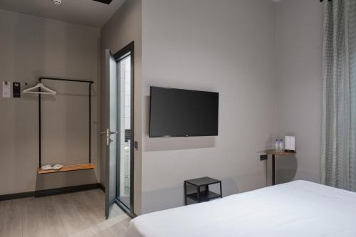 塔什干Sapiens Hotel的卧室配有一张床和壁挂式平面电视。