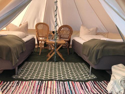 斯泰厄Helles Have Glamping的帐篷配有两张床和一张桌子及椅子