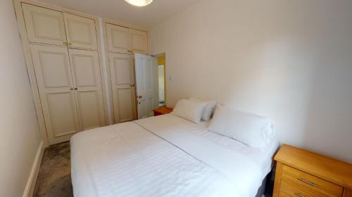 牛津The Bardwell的卧室配有白色的床和木制橱柜。