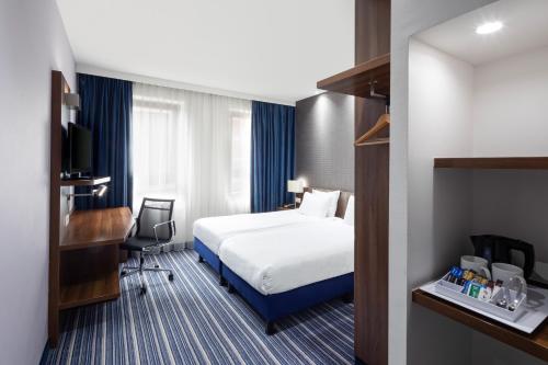 海牙海牙议会智选假日酒店的配有一张床和一张书桌的酒店客房
