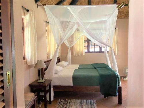 布拉瓦约Family Lodge in Natural African bush - 2113的一间卧室配有一张带天蓬的床