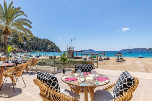 圣胡安包蒂斯塔El Somni Ibiza Dream Hotel by Grupotel的海滩旁带桌椅的天井