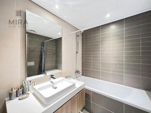 迪拜Mira Holiday Homes - Newly 2 bedroom in Dubai Marina with Canal View的一间带水槽、浴缸和镜子的浴室