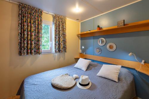 耶尔La Doucette, mobil-home climatisé au cœur du vignoble et à 50m de la mer的一间卧室,配有一张带两顶帽子的床