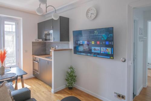 巴黎Paris Bercy - Charming Apartment 2 rooms的客厅设有厨房,墙上配有电视。