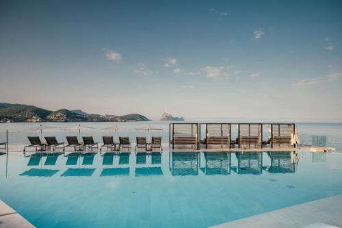 圣何塞7Pines Resort Ibiza, part of Destination by Hyatt的一个带椅子的游泳池,背景是大海
