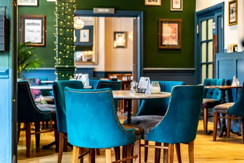 哈罗盖特The Inn at Cheltenham Parade的一间配备有蓝色椅子和桌子的用餐室