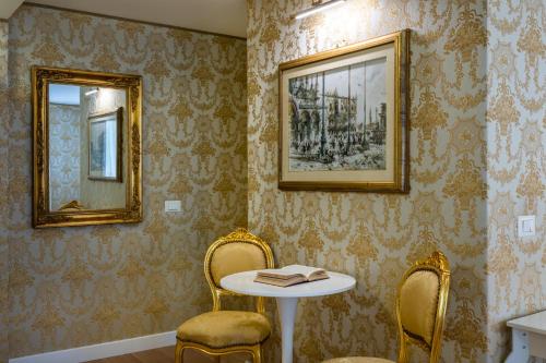 威尼斯Hotel Apostoli Garden的一间设有两把椅子、一张桌子和两面镜子的房间