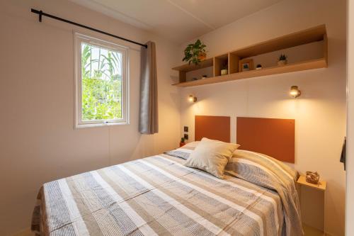 耶尔Le Palmier, mobil-home sans vis-à-vis idéalement situé entre mer et vignes的一间卧室设有一张床和一个窗口