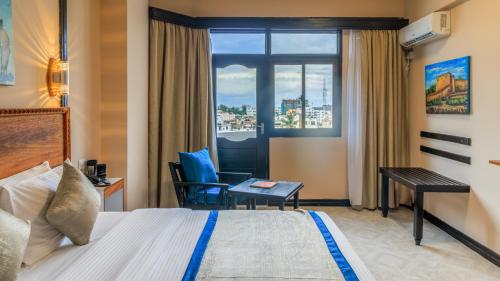 蒙巴萨Hotel Sapphire的配有一张床、一张书桌和一扇窗户的酒店客房