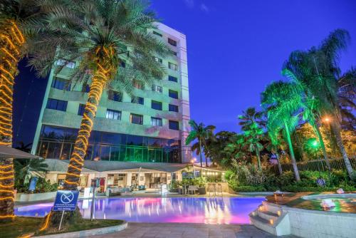 卡利卡利皇家NH酒店 的夜间有游泳池和棕榈树的酒店