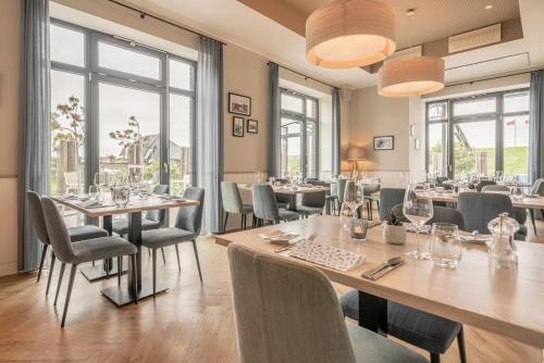 比苏姆Küstenperle Strandhotel & Spa的餐厅设有桌椅和窗户。