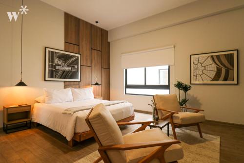 利马SoHo by Wynwood House的一间卧室配有一张床、两把椅子和一个窗户