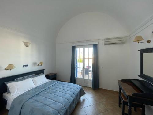 卡马利Leonidas Apartments的一间卧室配有一张床、一张书桌和一台电视