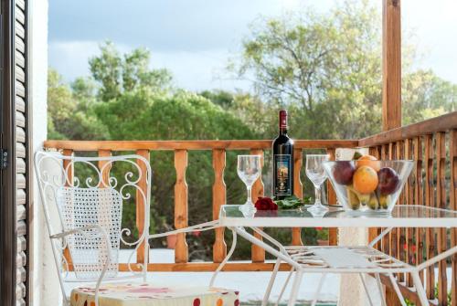 锡蒂亚Romanza Villas的门廊上的桌子,上面有一瓶葡萄酒和玻璃杯