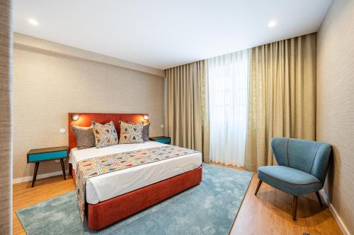 波尔图Casas do Porto - Ribeira Apartments的配有一张床和一把椅子的酒店客房