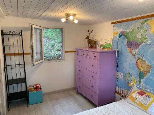 加桑Chalet dans le vert的卧室配有紫色梳妆台和墙上的地图