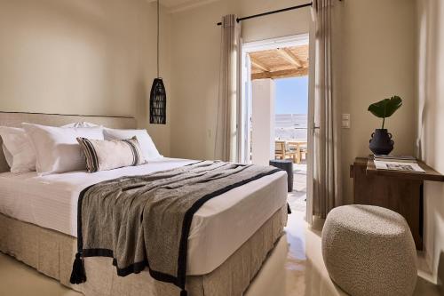 米克诺斯城Sharm Hotel Mykonos的卧室配有床、椅子和窗户。