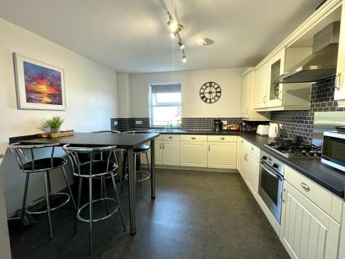 本莱赫Apartment 3 Benllech with Sea views的厨房配有白色橱柜和带凳子的桌子