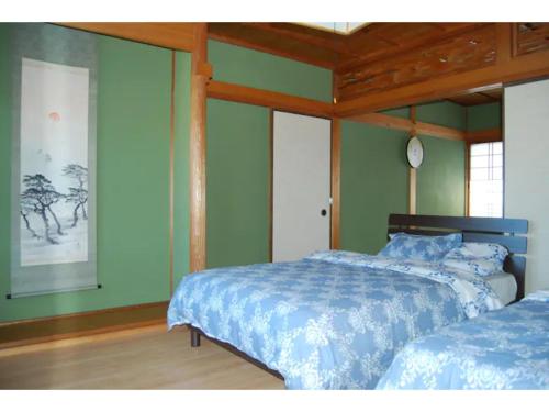 伊势市Minpaku Yagi - Vacation STAY 14700的一间卧室设有两张床,墙上挂着一个时钟。