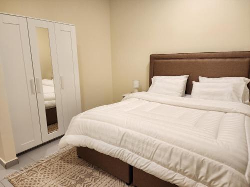 达曼Nesaj Villa的一间卧室配有一张带白色床单和镜子的大床
