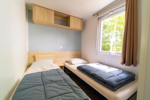 翁赞Mobil-home 6/8 personnes - Camping Siblu **** Domaine de Dugny的一间卧室设有两张床和窗户。