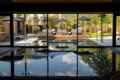 勒米尔蒙Best Western Premier Le Chapitre Hotel and Spa的一座带玻璃窗的别墅内的游泳池