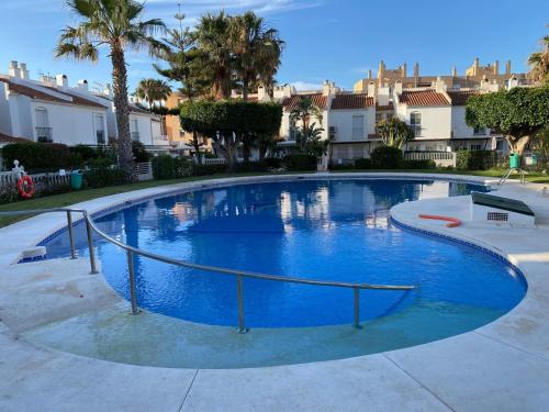 马拉加Malaga Chalet en Guadalmar的一座种植了棕榈树和房屋的大型蓝色游泳池