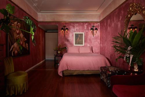 ElthamEltham Hotel NSW的粉红色的卧室配有床和椅子