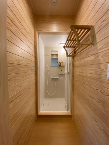 新宫市AJITO Hostel & CafeBar的设有带木墙的浴室内的步入式淋浴间