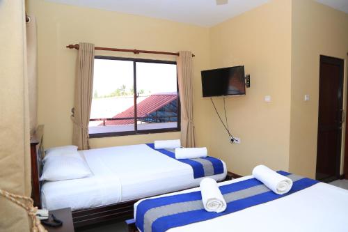 贾夫纳PJ Hotels Jaffna的酒店客房设有两张床和窗户。